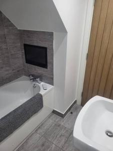 TV y baño con bañera y aseo. en Modern Apartment Nottingham en Nottingham