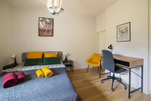 Un dormitorio con una cama con almohadas de colores y un escritorio. en Apartment Rajzefiber - Spodek - MCK - NOSPR, en Katowice