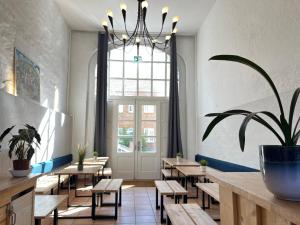 a restaurant with tables and chairs and a chandelier at Blue Doors Hostel Altstadt in Rostock