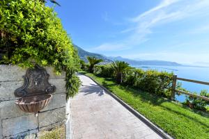 a brick path next to a retaining wall with a view of the water at Kemì Luxury Suites in Vietri sul Mare