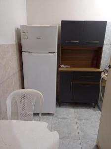 eine Küche mit einem weißen Kühlschrank sowie einem Tisch und einem Stuhl in der Unterkunft Residencial Barbosa - Apto 102 in Macaé