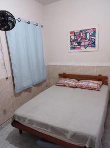 uma cama num quarto com uma janela e uma cortina em Residencial Barbosa - Apto 102 em Macaé
