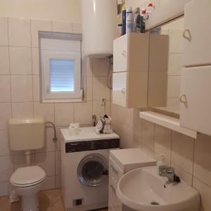 een kleine badkamer met een wasmachine en een wastafel bij Sunny in Sukošan