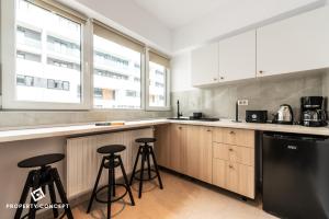 eine Küche mit weißen Schränken und Barhockern in der Unterkunft Central Residence Apartment 928 in Vatra Mînăstirii Cotroceni