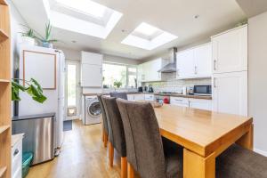 a kitchen with a wooden table and chairs at Charming Retreat West London - Spacious & Modern in Hanwell