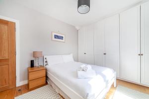 a white bedroom with a bed with two towels at Charming Retreat West London - Spacious & Modern in Hanwell