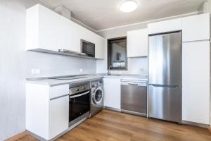 eine Küche mit weißen Schränken und einem Kühlschrank aus Edelstahl in der Unterkunft Apartamentos Garden & Sea Boutique Lodging by LIVVO in Morro del Jable