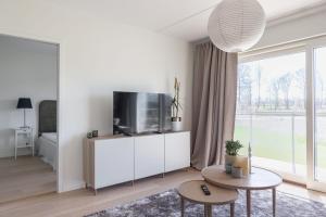 a white living room with a tv and a table at The Oak - Ekerum Öland in Borgholm