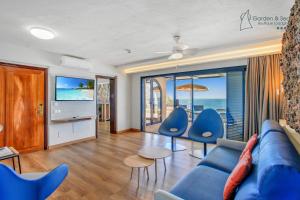 ein Wohnzimmer mit einem blauen Sofa und Stühlen in der Unterkunft Apartamentos Garden & Sea Boutique Lodging by LIVVO in Morro del Jable