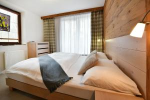 a bedroom with a bed with a wooden headboard at APLEND Hotel Kukučka in Vysoke Tatry - Tatranska Lomnica.