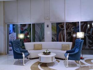 a lobby with a white couch and two blue chairs at 1BR and Studio Condo Unit @ 150 Newport near NAIA 3 in Manila