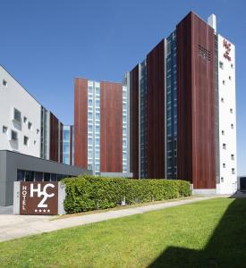 two tall buildings with grass in front of them at H2C Hotel Milanofiori in Assago