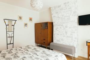 1 dormitorio con 1 cama, armario y TV en Chez Pépé Merle - Chambre d'hôte au coeur de Paris en París