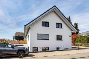 een wit huis met een auto ervoor geparkeerd bij Stegmann Horn in Gaienhofen