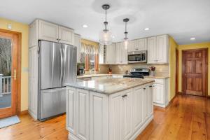 a kitchen with white cabinets and a stainless steel refrigerator at 4 Lookout Point Road Plymouth Z Ocean House in Sandwich