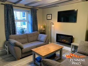 a living room with a couch and a fireplace at Forge Cottage - Modern Cottage in Central Location in Haltwhistle