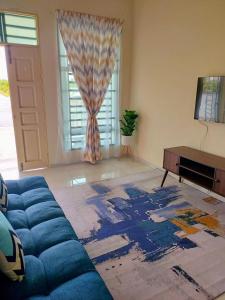 a living room with a blue couch in front of a window at SAFI Homestay Perlis in Arau