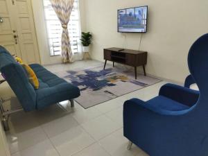 a living room with two blue chairs and a tv at SAFI Homestay Perlis in Arau