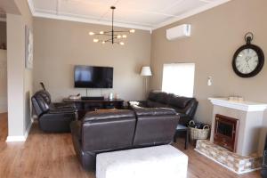 a living room with leather furniture and a fireplace at Scenic two bedroom house with splash pool in Cape Town