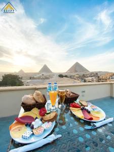 開羅的住宿－Egypt Pyramids Inn，两盘食物放在桌子上,有金字塔背景