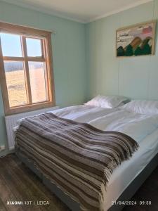 Un dormitorio con una cama con una manta. en Happy-Cove Guesthouse - by the sea, en Bakkafjörður