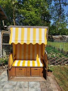 un banc avec un auvent rayé jaune et blanc dans l'établissement Ferienwohnung "Am Stadtrand", à Garz