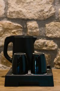 duas canecas de café preto sentadas num suporte preto em Άνδηρο em Synikia Mesi Trikalon