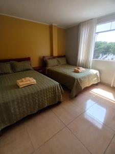 um quarto de hotel com duas camas e uma janela em "A y J Familia Hospedaje" - Free tr4nsfer from the Airport to the Hostel em Lima