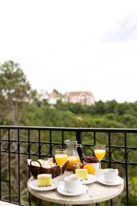 una mesa con comida y bebida en el balcón en Pousada Lá Bas, en Campos do Jordão