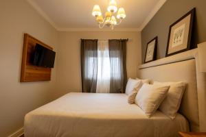 1 dormitorio con 1 cama con lámpara de araña y ventana en Pousada Lá Bas, en Campos do Jordão