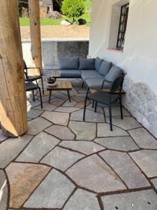 a patio with chairs and a couch on a stone floor at Casa Dalsass in Cavedago