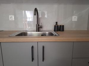 um lavatório de aço inoxidável numa cozinha com armários brancos em modern apt near Heraklion city & airport em Néa Alikarnassós