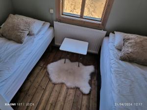 a bedroom with two beds and a table on the floor at Happy-Cove Guesthouse - by the sea in Bakkafjörður