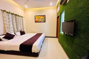 Hotel The Galaxy في Dabok: غرفة نوم بسرير وتلفزيون بشاشة مسطحة