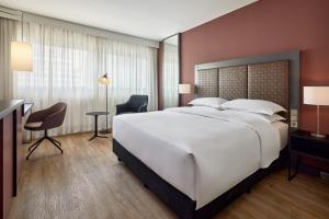 a large bedroom with a large white bed and a desk at Sheraton Frankfurt Airport Hotel & Conference Center in Frankfurt