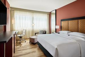 フランクフルト・アム・マインにあるシェラトン フランクフルト エアポート ホテル＆カンファレンス センターの大きなベッドとデスクが備わるホテルルームです。