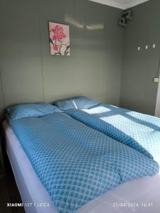 a bed with a blue comforter in a bedroom at Happy-Cove Guesthouse - by the sea in Bakkafjörður