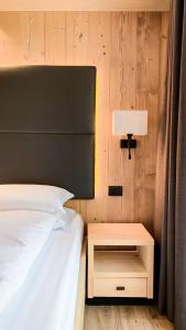 a bedroom with a bed and a night stand with a lamp at Hotel La Montanara Predazzo in Predazzo