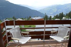 two chairs on a balcony with a view of mountains at Appartement 7 couchages in Montvalezan