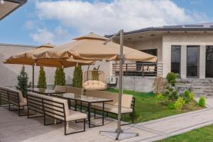 un patio con mesa, sillas y sombrilla en Chic Villa with many amenities, one of a kind in the country, en Arzni
