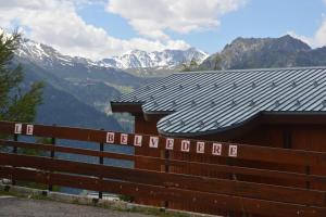 a building with a roof with mountains in the background at Appartement 7 couchages in Montvalezan