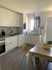 eine Küche mit weißen Schränken und einem Tisch und einem Tisch und einem Esszimmer in der Unterkunft Casa de Praia Quiaios in Quiaios