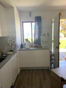 eine Küche mit weißen Schränken und einem Fenster in der Unterkunft Casa de Praia Quiaios in Quiaios