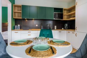 a kitchen with a white table and green cabinets at Apartament Izerka z Sauną in Świeradów-Zdrój