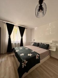 een slaapkamer met een bed met een zwarte deken met bloemen bij Luna Apartament in Timişoara