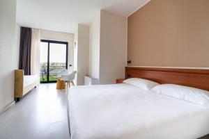 una camera da letto con un grande letto bianco e una finestra di Hotel Ristorante Al Fiore a Peschiera del Garda