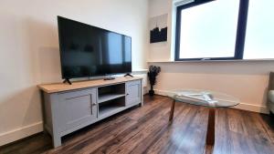 a living room with a flat screen tv on a entertainment center at Luxury 1 bed apartment 10 mins from Bham City Centre in Birmingham