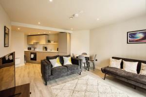a living room with two couches and a kitchen at St Martin's Place Apartment - Bham City Centre in Birmingham