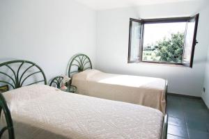 two beds in a room with a window at Bari Sardo Suite Padronale in Bari Sardo