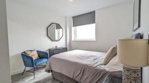1 dormitorio con cama, silla y espejo en Modern 2 Bed Apt - 15 Mins to Birmingham Centre, en Birmingham
